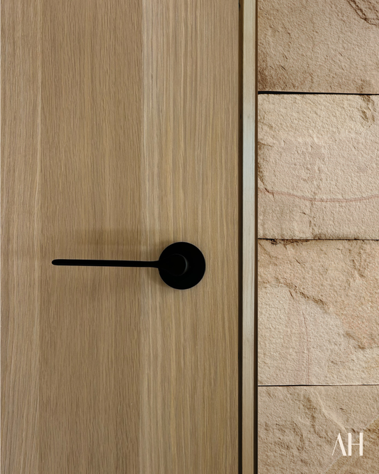Wooden door with a black handle on a stone wall background