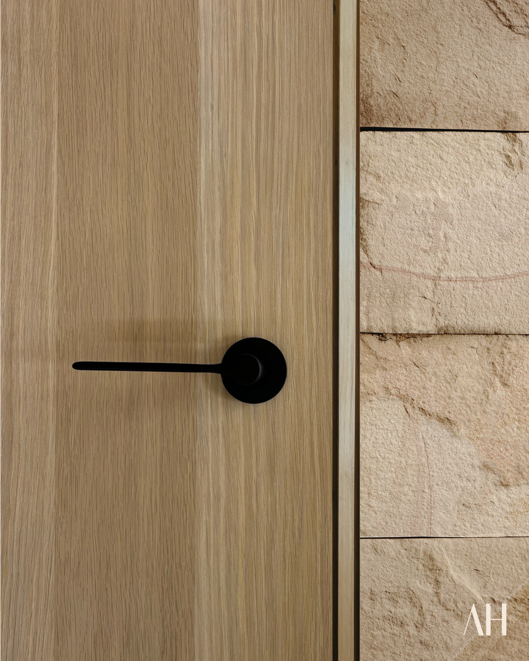 Wooden door with a black handle on a stone wall background